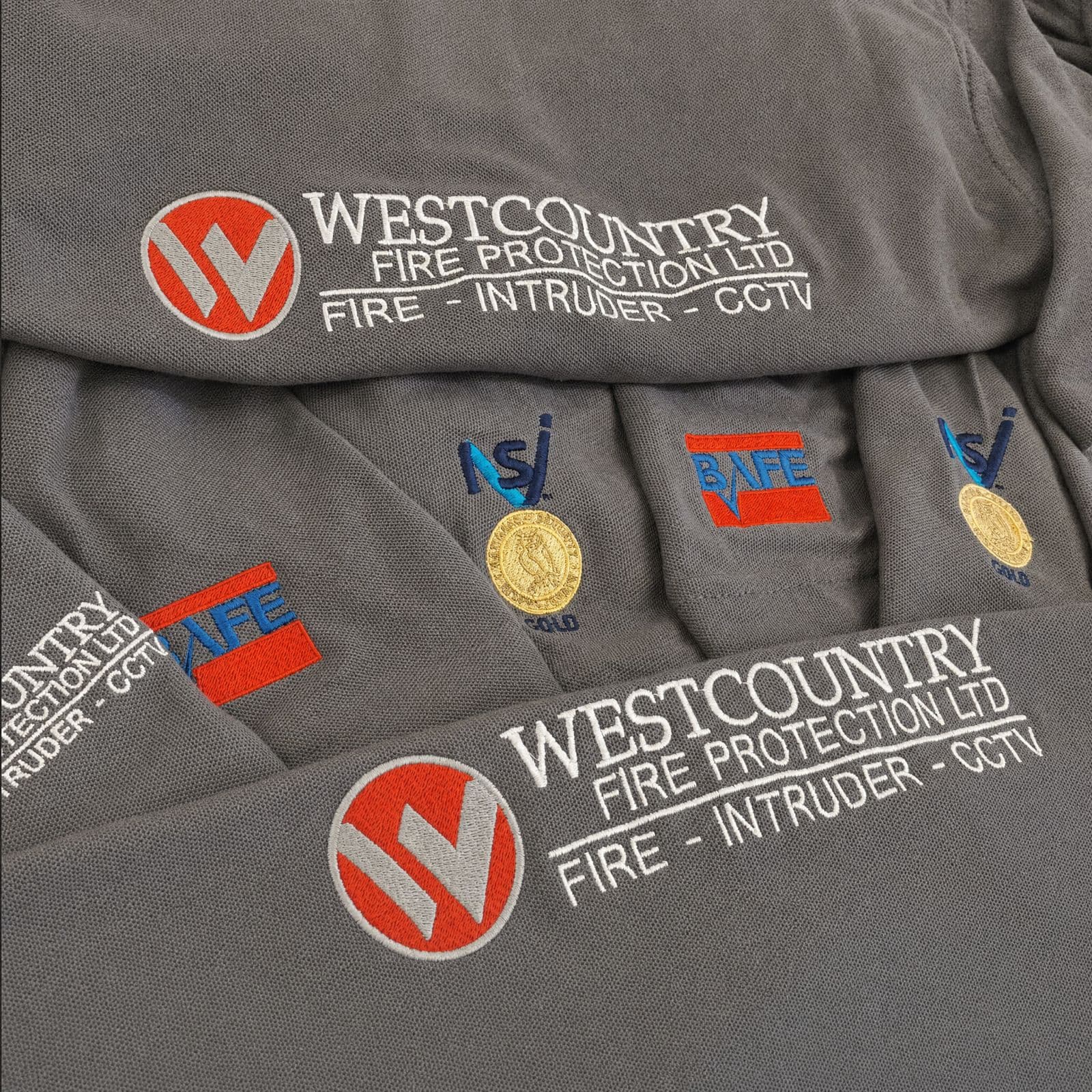 Grey polo shirts embroidered with the Westcountry Fire Protection logo and NSI Gold and BAFE accreditation badges