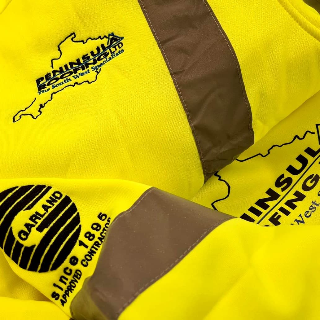 Stack of yellow hi-vis jackets with reflective stripes, embroidered with the Peninsula Roofing and Garland approved-contractor logos