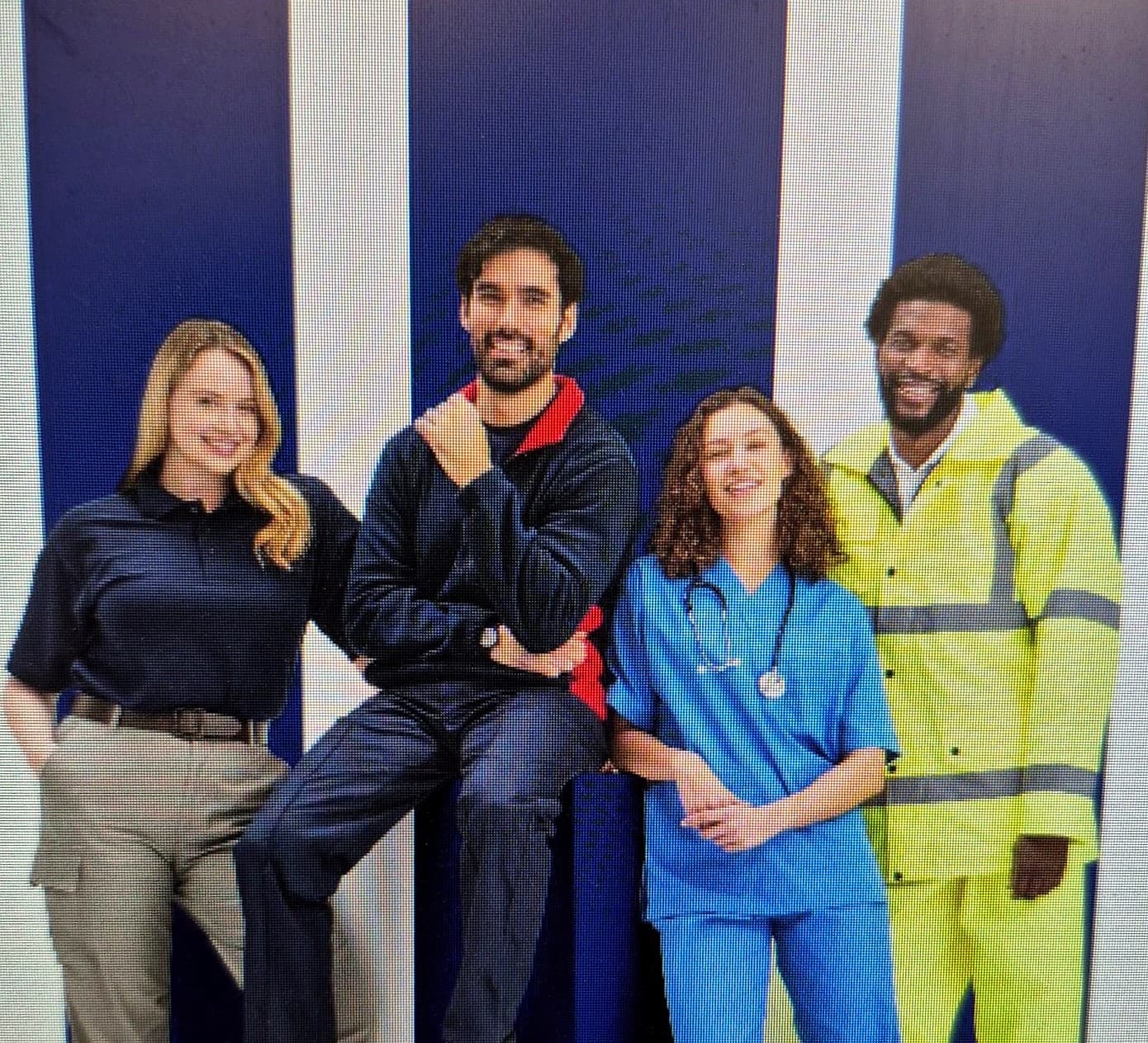 Four people in different workwear ranges — a navy polo with cargo trousers, a padded work jacket, blue medical scrubs and a yellow hi-vis suit
